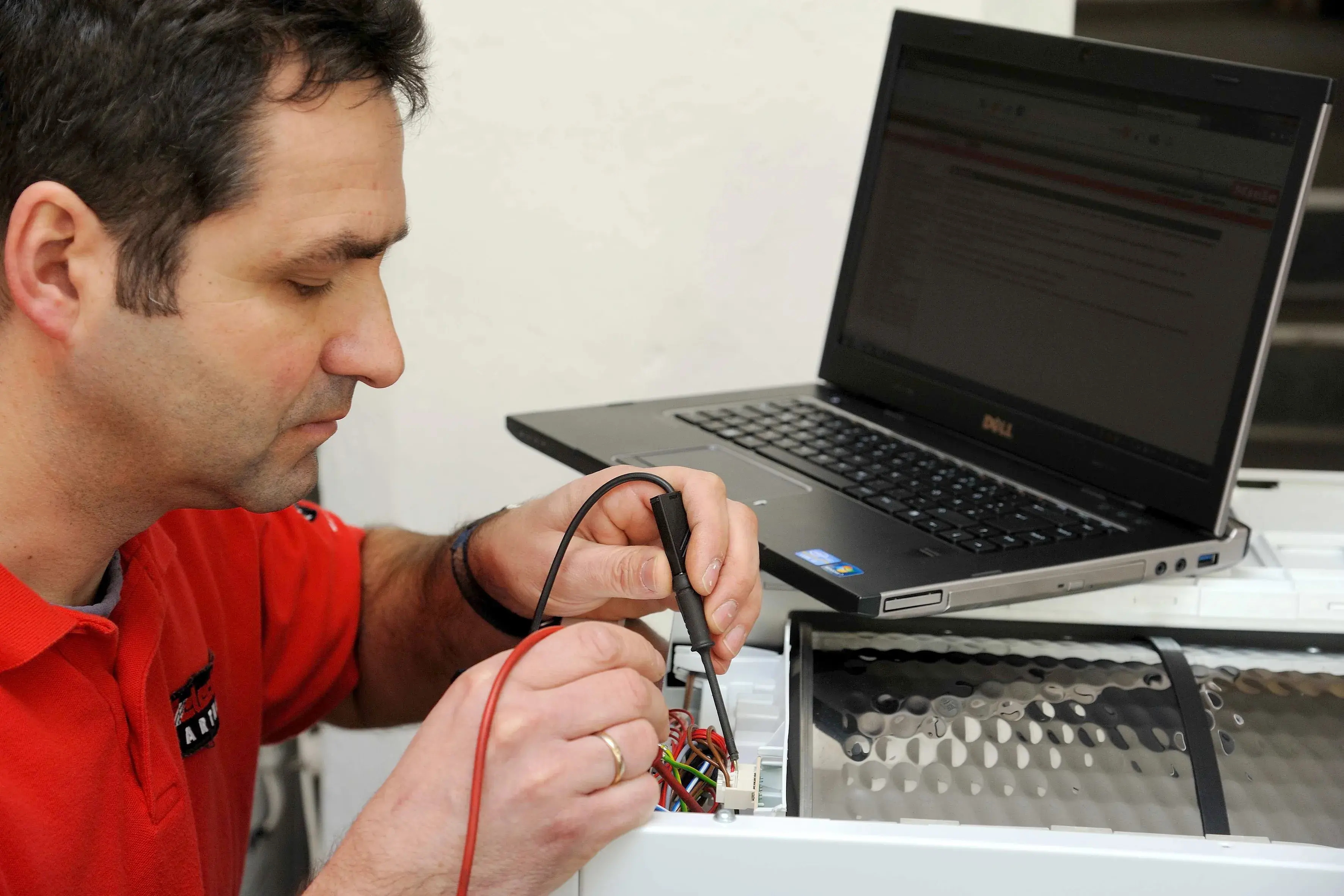 Bild von einem Elektriker der Firma Grotevendt der ein Hausgerät repariert